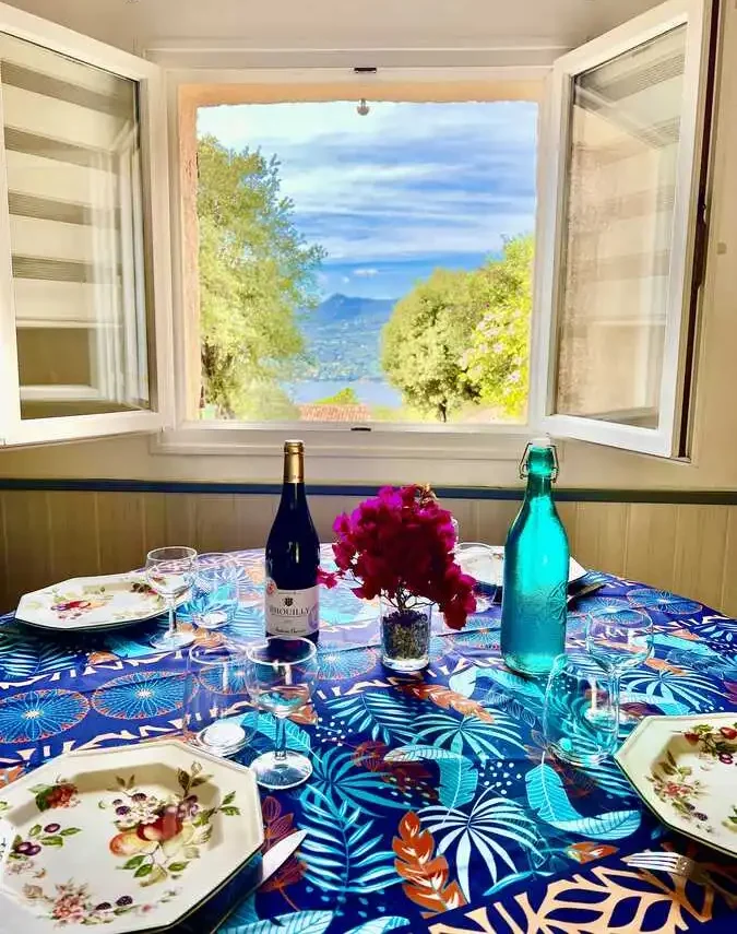 Vue sur la mer depuis une table de salle à manger joliment dressée dans une maison en Corse.