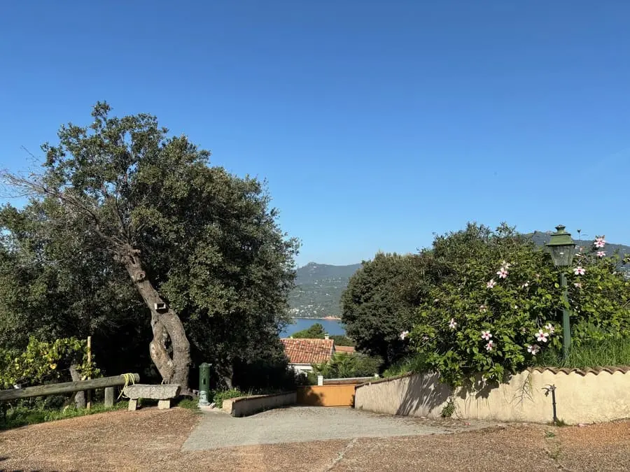 Vue extérieure de la propriété en Corse, donnant sur des collines verdoyantes et la mer au loin.