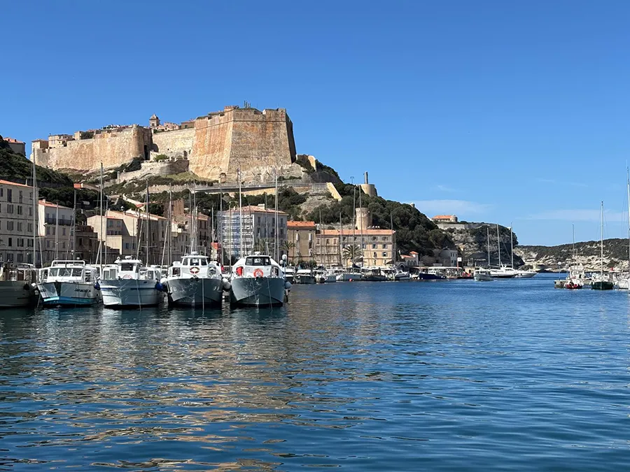 Fort et citadelle de Bonifacio dominant le port, Corse du Sud, avec bateaux et ciel bleu, vacances historiques.