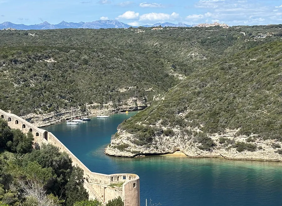 Panorama sur la marine de Bonifacio, Corse du Sud, avec falaises, mer et montagnes au loin, pour vacances grandioses.