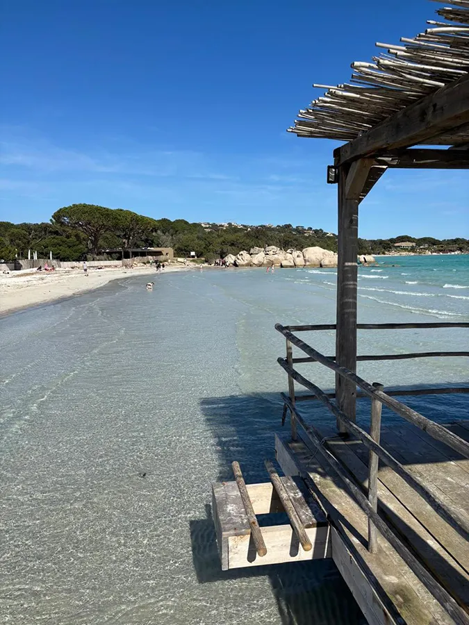 Plage de sable blanc et eaux peu profondes en Corse du Sud, avec ponton, idéale pour vacances en famille.