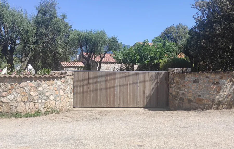 Portail d'entrée en bois et murets de pierre d'une villa à louer en Corse du Sud. Sécurité et intimité pour votre location Caseddu Jardin et Mer.