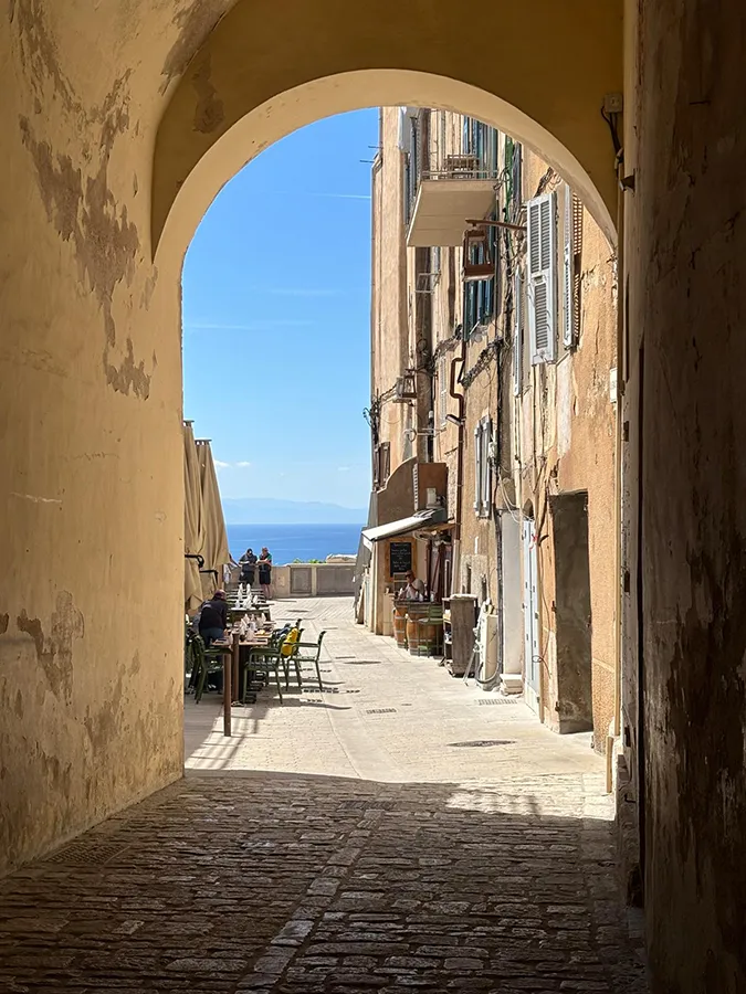 Rue historique de Bonifacio, Corse du Sud, avec voûte, restaurants et vue mer, idéale pour vacances.