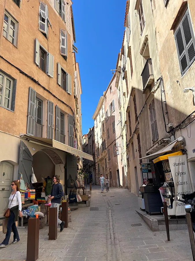 Rue étroite et historique de Sartène en Corse du Sud, avec façades typiques et boutiques, ambiance village.